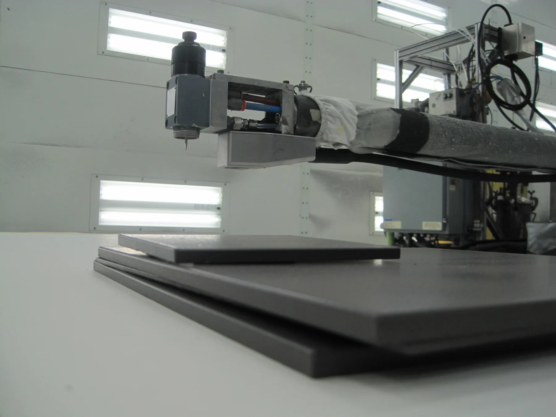 A robotic arm carrying a terahertz coating-thickness probe and spray attachment, positioned over an aircraft inlet component